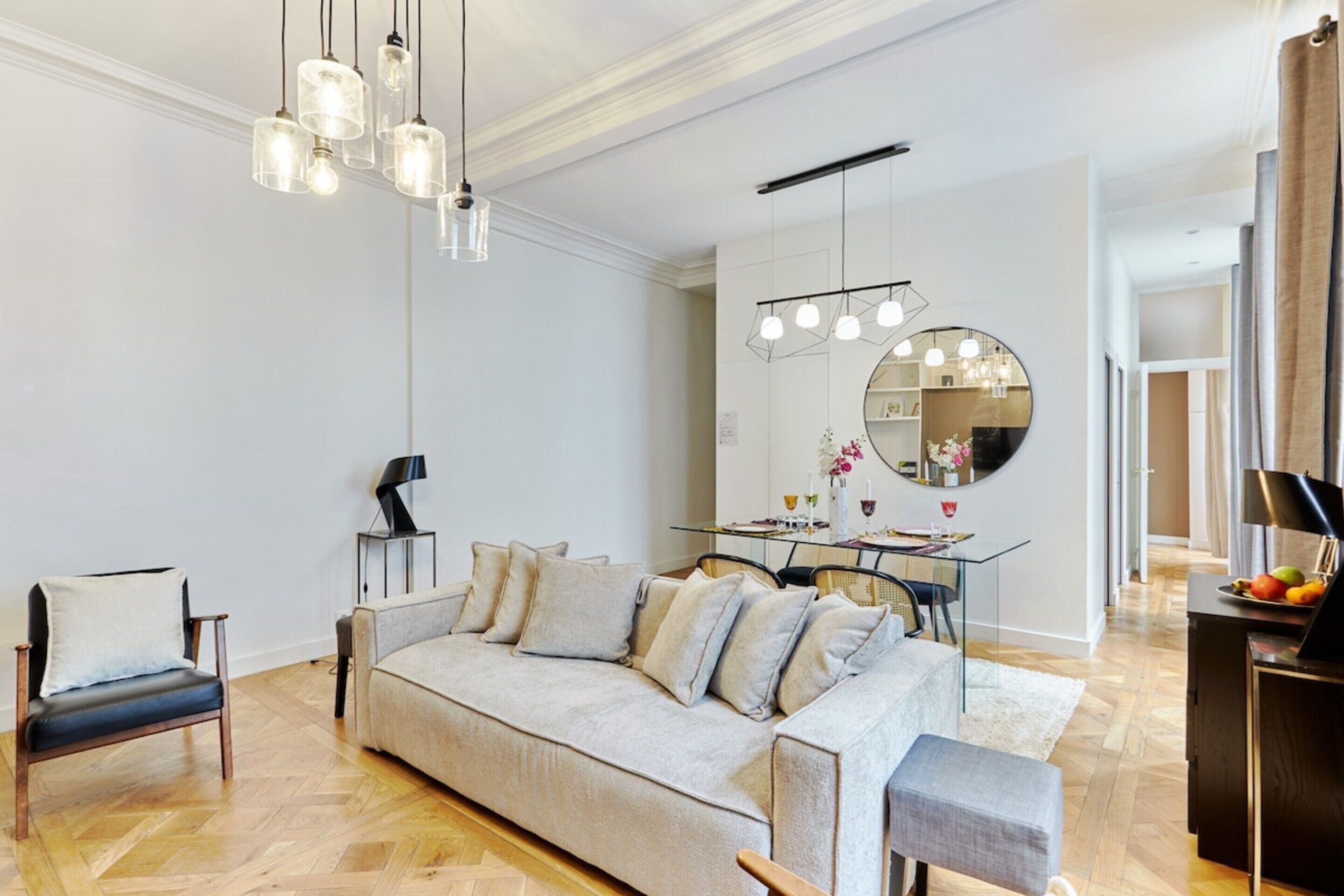 A modern living room with a sofa, a dining table, and a chandelier.
