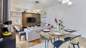 Un soggiorno moderno con un divano, un tavolo da pranzo in vetro e una TV a parete.
