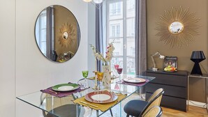 Un'area pranzo moderna con un tavolo in vetro, sedie e uno specchio decorativo.