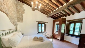 A bedroom with a large bed, wooden beams, stone wall, and windows. - New! Restored farmhouse,private pool,plunge pool, river! Walk pizzeria. Perfect! (Toscana)