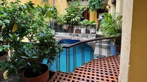 Une cour avec une piscine, des plantes en pot et un escalier menant à un balcon.