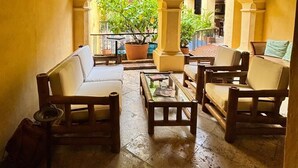 Un patio intérieur accueillant, avec des meubles en bois, un ventilateur de plafond et une vue sur une cour intérieure, accessible par des arcades.