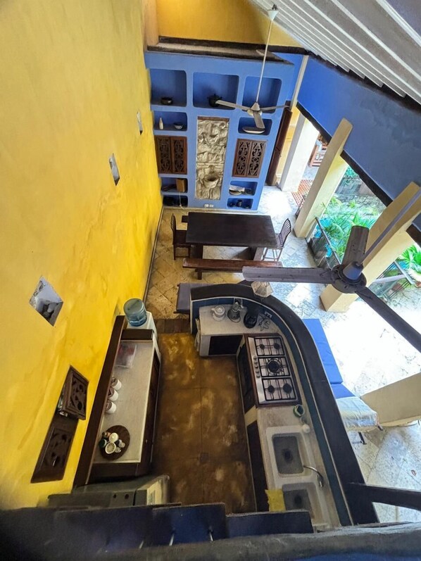 A kitchen with a gas stove, a sink, and a small countertop. There is a window with a view of greenery outside.