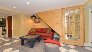 A living room with a red sofa, a coffee table, and a grey ottoman. There is a wooden door with glass panels and a framed picture on the wall. - Specious one bedroom apartment in upscale neighbourhood in Leaside Toronto.  (Toronto)