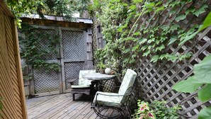 A wooden deck with a table and chairs, surrounded by a wooden fence and greenery. - Specious one bedroom apartment in upscale neighbourhood in Leaside Toronto.  (Toronto)