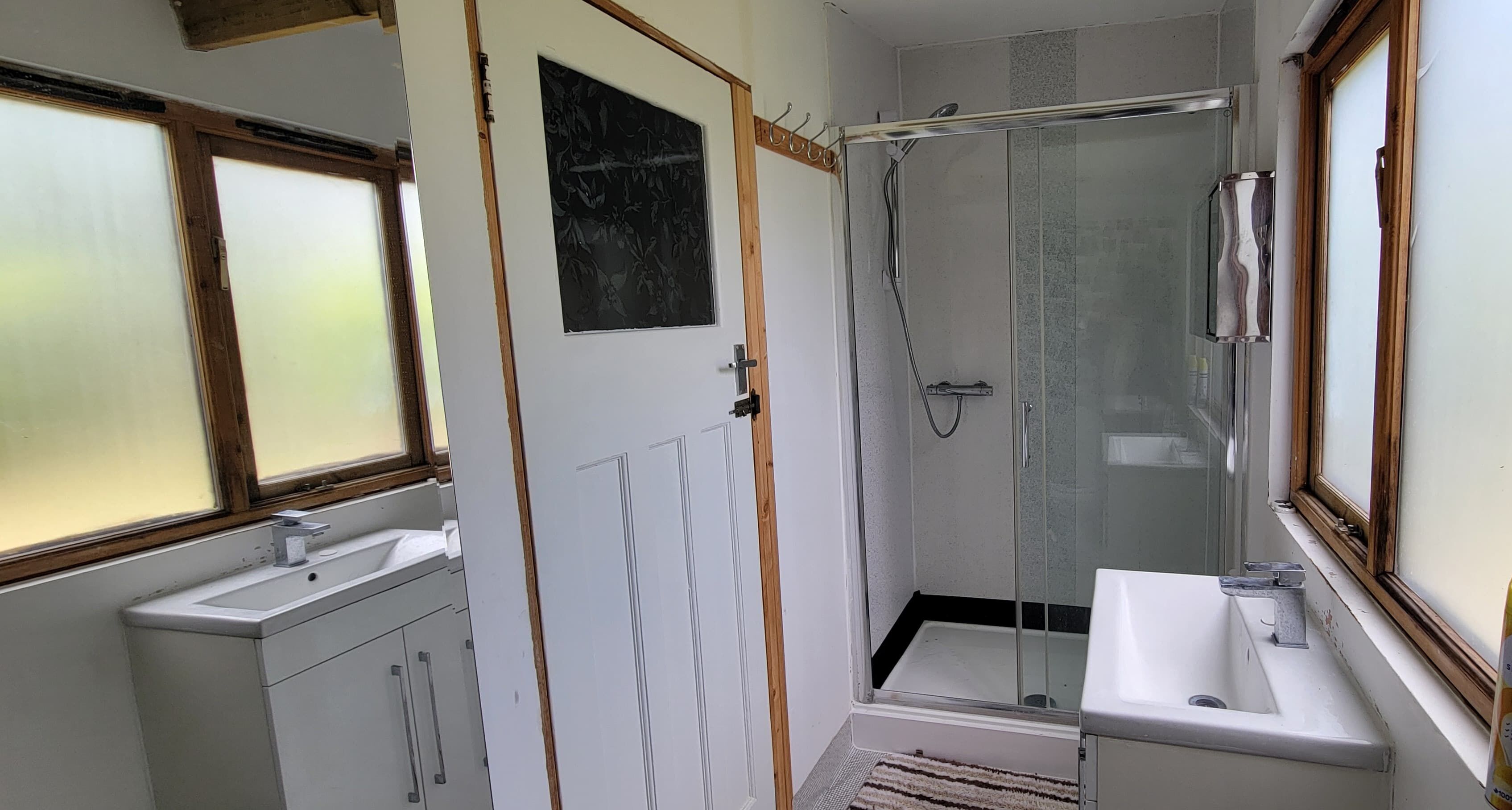 A bathroom with a glass shower enclosure, a sink, and a mirror.