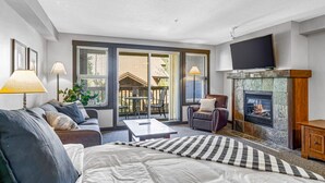 Un salon moderne avec une cheminée, un canapé, une table basse et un téléviseur fixé au mur.