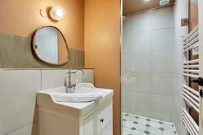 Een badkamer met een wastafel, spiegel en douche.