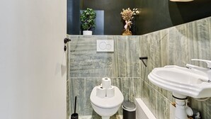Une salle de bain moderne avec des toilettes, un lavabo et une petite plante en pot accrochée au mur.