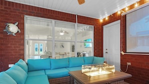 A cozy living room with a blue sectional sofa, a wooden coffee table, and a brick wall. - Private spacious resort, jumbo heated salt water pool/spa, game room, office (Navarre)