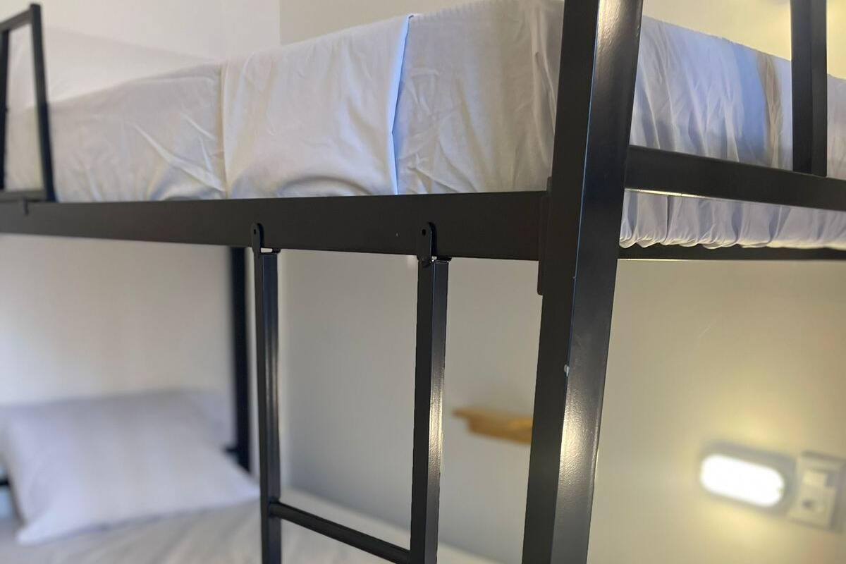 Una cama litera con ropa blanca y estructura metálica.