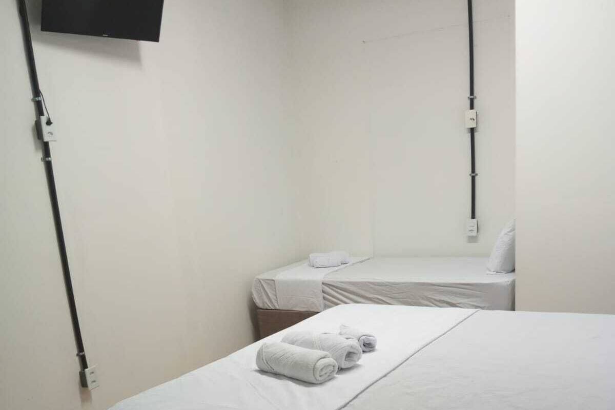 Una habitación de hotel con una cama grande, una cama más pequeña y un televisor montado en la pared.