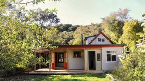 A single-story house with a red roof, a covered porch, and a small garden area.