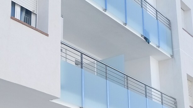 A multi-story building with balconies, a visible storefront, and a window with a metal grill. - Residential apartment very close to the sea  (Blanes)