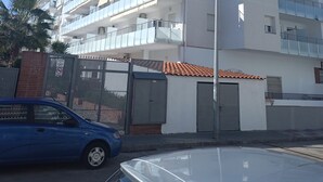 A multi-story building with balconies, a gated entrance, and a parked car. - Residential apartment very close to the sea  (Blanes)