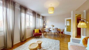A modern living room with a dining area, large windows, and a unique door design. - Chez Léa + 1 parking (Colmar)