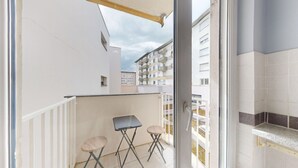 A balcony with a white railing, two foldable chairs, and a small table. - Chez Léa + 1 parking (Colmar)