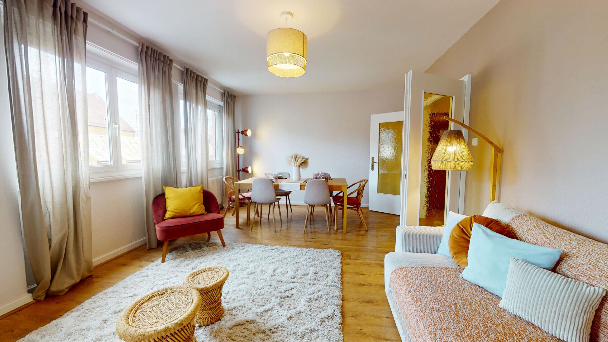 Una sala de estar con sofá, sillas, una mesa de comedor y una escalera.