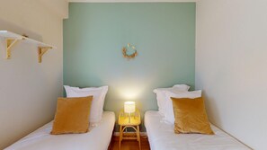 Una stanza con due letti, un tavolino, uno scaffale a parete e una ghirlanda decorativa.