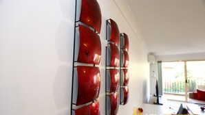 A modern interior with a wall-mounted red abstract art piece and a dining area with a table and chairs.