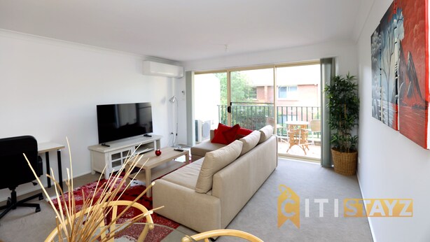 A modern living room with a sofa, TV, and a dining area.