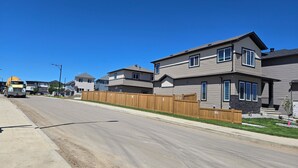 A residential street with houses, a concrete road, and a construction vehicle. - President's Choice: Lofty Guest Suite Near Airport  (Edmonton)
