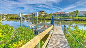 A wooden dock leading to a marina with boats, surrounded by lush greenery and residential buildings in the background. - Waterfront Paradise in Apollo Beach, with all the amenities you can think of. (Apollo Beach)