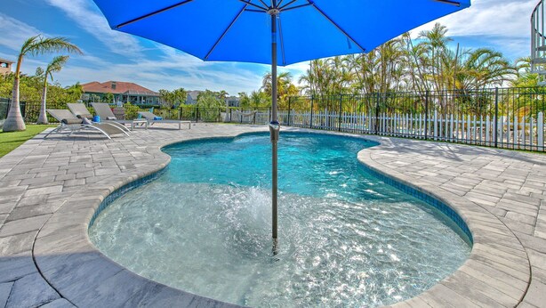 A swimming pool with a blue umbrella, surrounded by a brick patio and palm trees. - Waterfront Paradise in Apollo Beach, with all the amenities you can think of. (Apollo Beach)