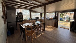A kitchen with wooden cabinets, a dining table with chairs, and a refrigerator.