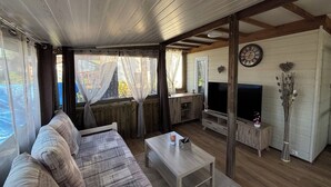 A cozy living room with a sofa, TV, and wooden beams.