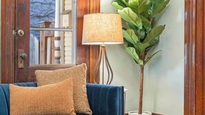 En stue med en blå sofa, et glasbord, en lampe og en potteplante.