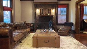 A cozy living room with a fireplace, leather furniture, and a vintage suitcase. - The Goodale Park Flat (Columbus)