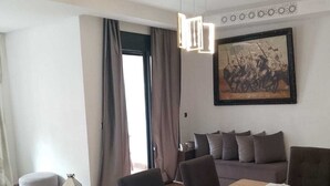 Een moderne woonkamer met een eettafel, stoelen, een bank en een schilderij aan de muur.