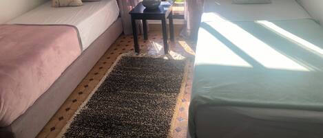 A room with two single beds, a small table, and a window with curtains.