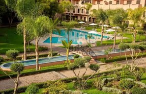 Une piscine entourée de palmiers et de verdure, avec un bâtiment en arrière-plan.