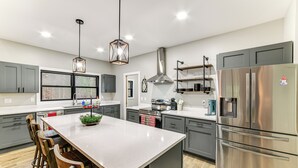 Una cocina moderna con armarios grises, electrodomésticos de acero inoxidable y una isla central con taburetes de bar.