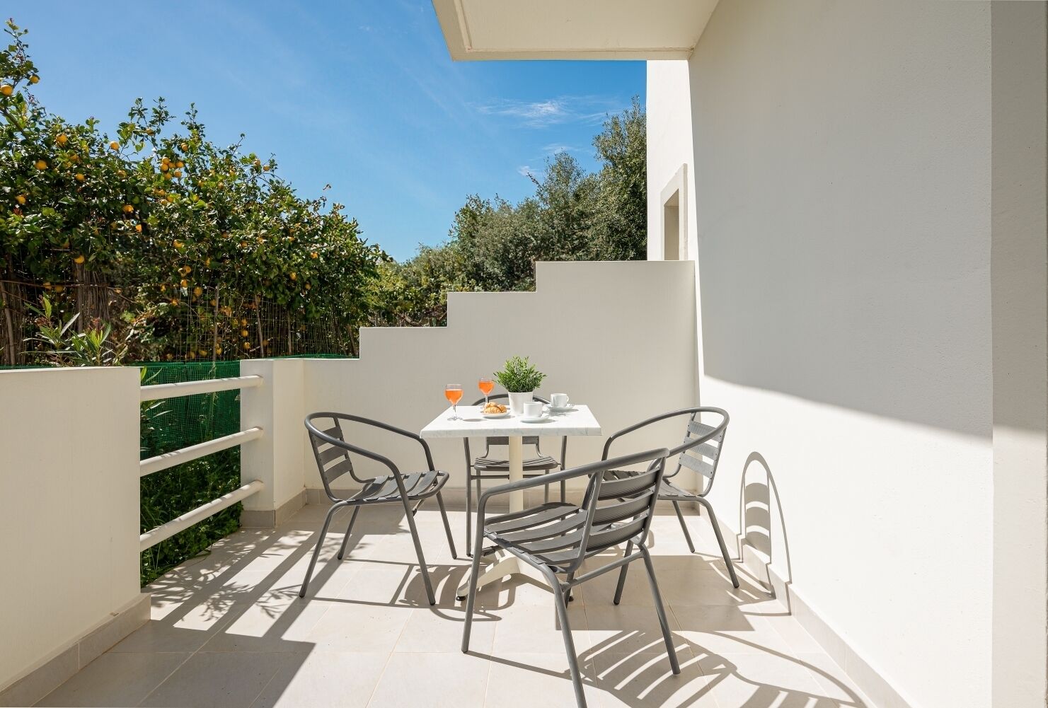Ein Balkon mit Tisch und Stühlen, einem kleinen Topfpflanzen und einem Glas Orangensaft.
