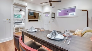 Un comedor con una mesa de madera dispuesta para dos personas, un ventilador de techo y un ventanal con vistas a árboles.