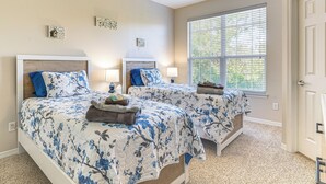 A bedroom with two beds, each with a floral bedspread, bedside lamps, and a window with blinds. - 2 Mi to Texas A&M: Unit w/ Pool & Hot Tub Access (College Station)