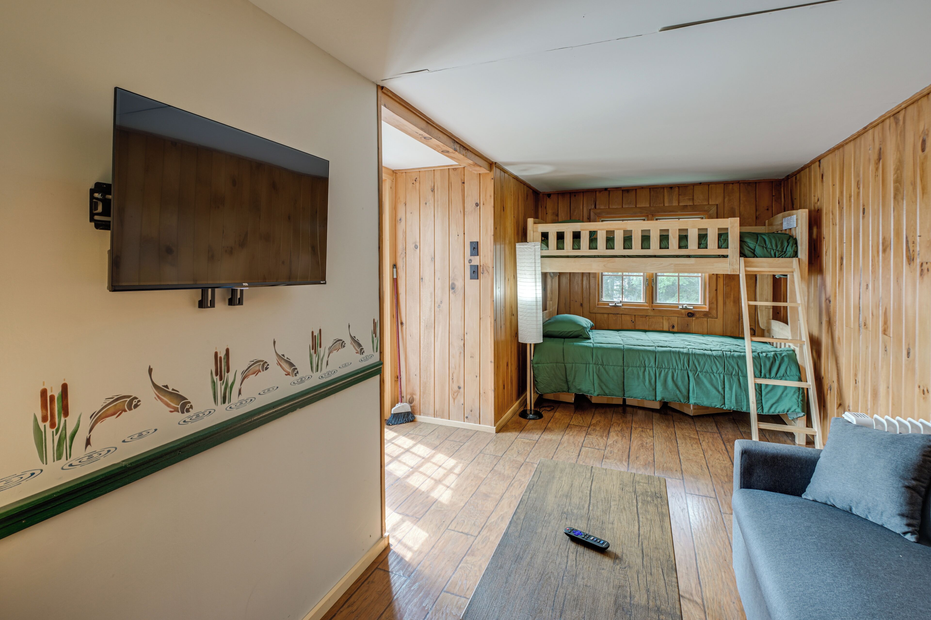 A room with a bunk bed, a television mounted on the wall, and a window.