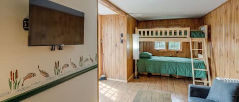A room with a bunk bed, a television mounted on the wall, and a window.