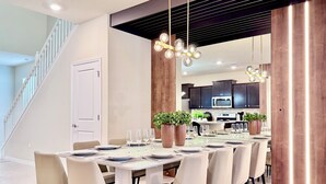 A modern dining area with a long table, chairs, and a chandelier. - Spacious 7BR Clermont Retreat w/ 4 King Beds, Modern Comfort & Great Location (Clermont)