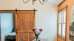 Una mesa de comedor de madera con sillas, una lámpara de araña y un florero con flores.
