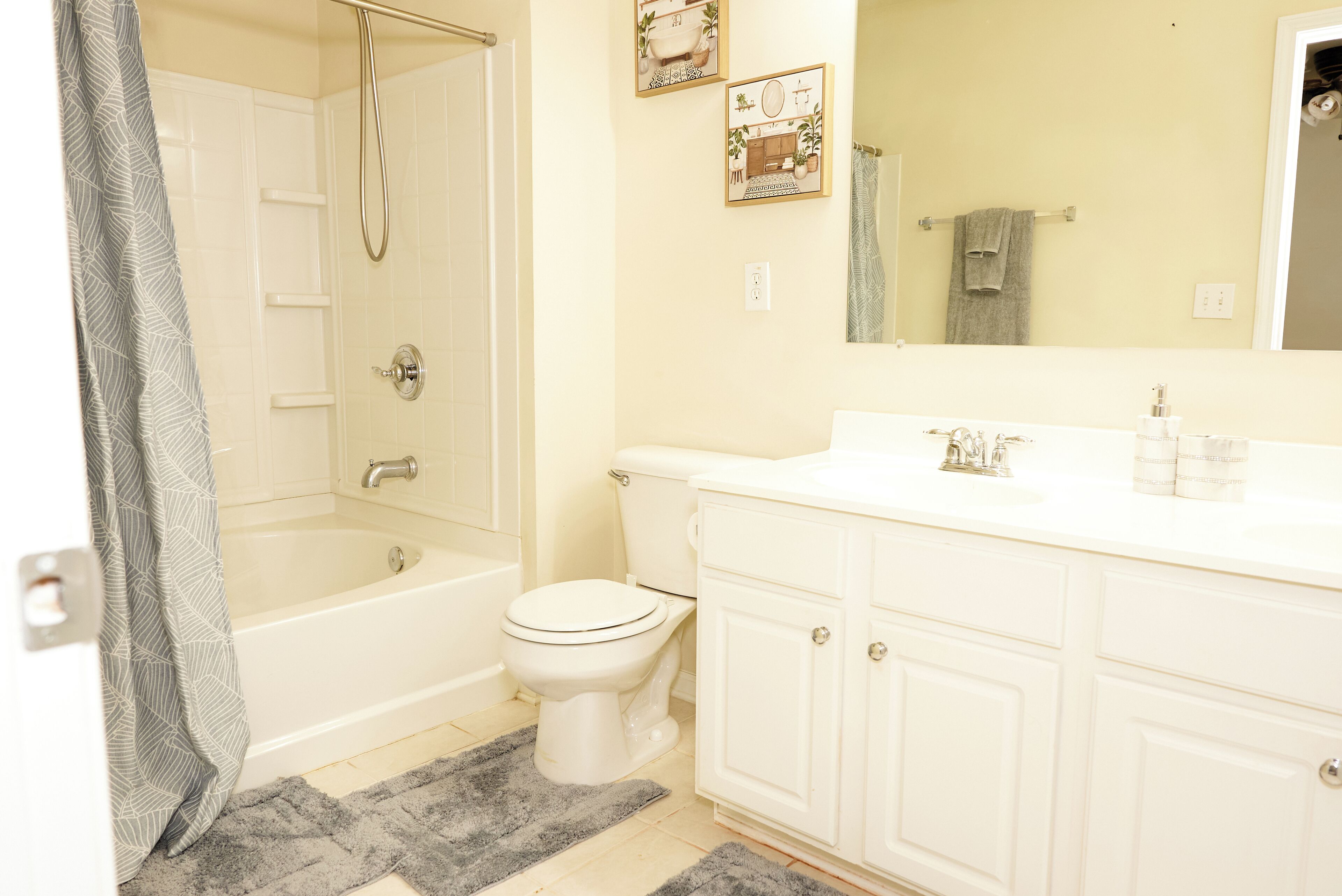 A bathroom with a bathtub, toilet, and vanity with cabinets.