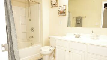 A bathroom with a bathtub, toilet, and vanity with cabinets.