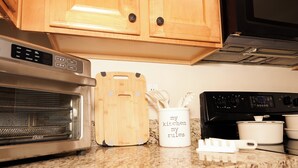 A kitchen with wooden cabinets, a microwave, an oven, a cutting board, a mug, and a set of measuring cups. - Charming 3-bedroom townhome in Duluth  (Duluth)