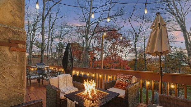 A deck with outdoor furniture, a fire feature, and string lights.