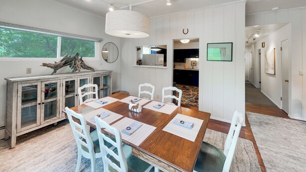 A modern dining area with a wooden table, white chairs, and a decorative cabinet. - Apt Getaway In Downtown Bozeman! (Bozeman)