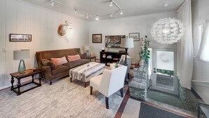 A living room with a brown sofa, a white armchair, a patterned rug, and a ceiling light fixture. - Apt Getaway In Downtown Bozeman! (Bozeman)