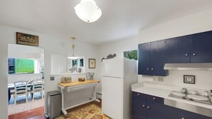 A compact kitchen with a refrigerator, stove, and a sink. There is a dining area with chairs and a table. - Apt Getaway In Downtown Bozeman! (Bozeman)